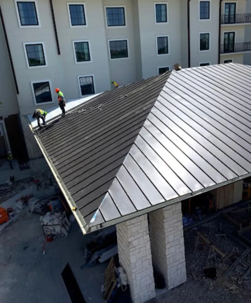 Crew installing standing seam metal roof panels on a commercial project in Mint Hill
